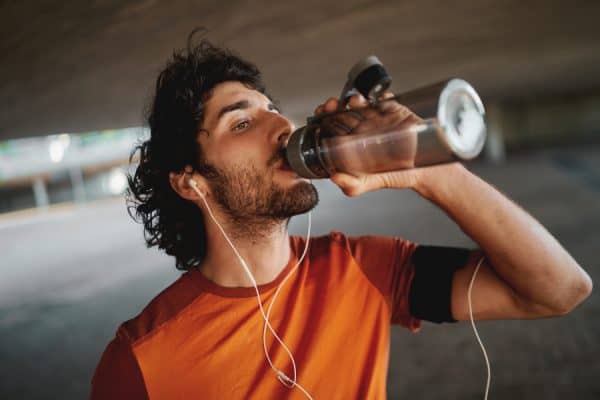Man in an orange shirt taking a break from running to drink water from a bottleless office water cooler in Austin TX.