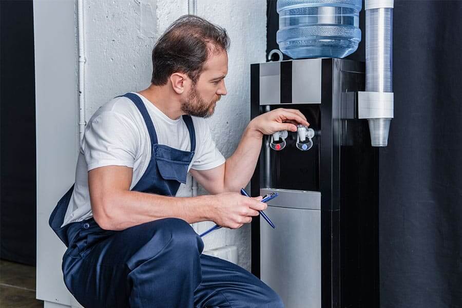 Man cleaning and maintaining a water cooler