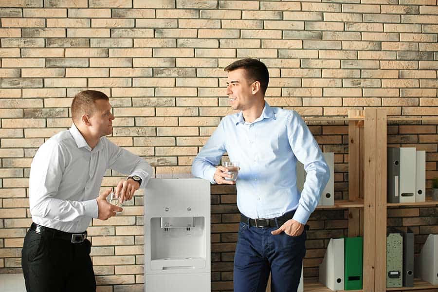 Employees chatting by a bottleless water cooler