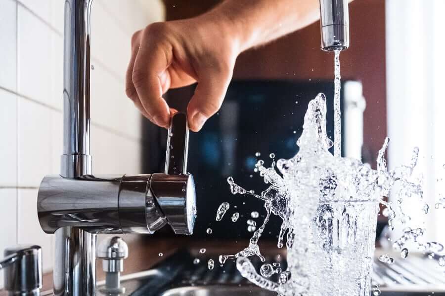 A person's hand turning the water on from a faucet to drink Austin tap water.