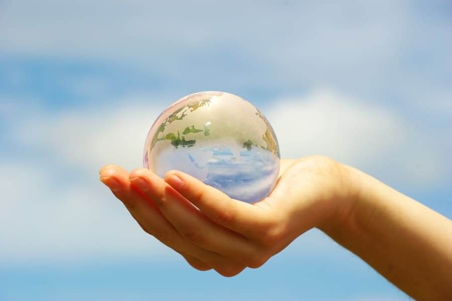 Hand holding a glass Earth representing eco-friendliness with office water filtration in Austin.