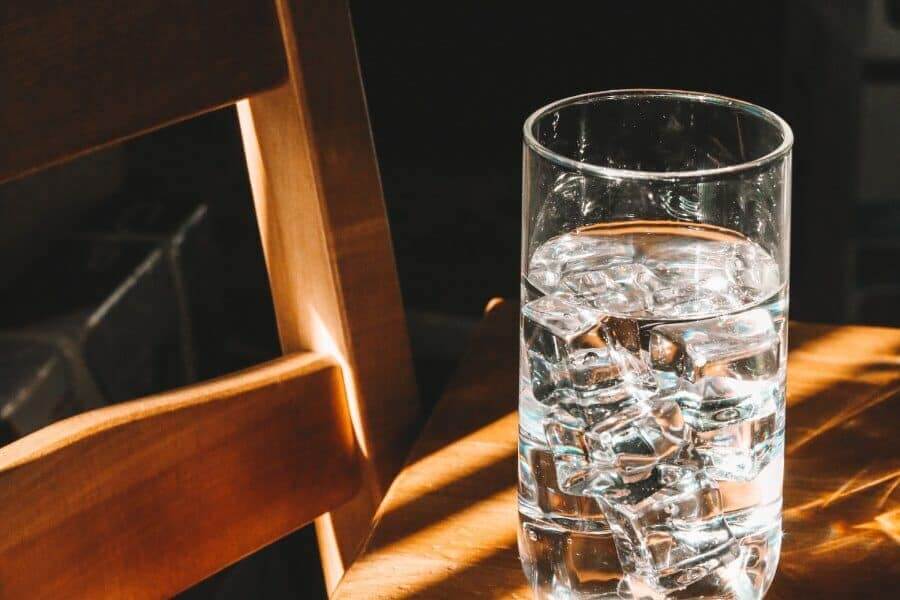system of water purification in Austin TX serves drinking water in a clear glass on a wooden table