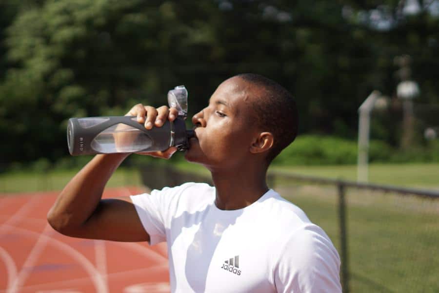 an athlete drinking water on the running track