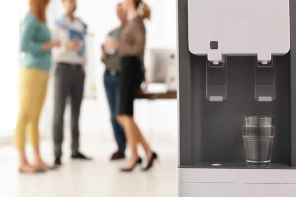Office employees gathering at bottleless water cooler - optimal workplace hydration with Austin TX water coolers for business
